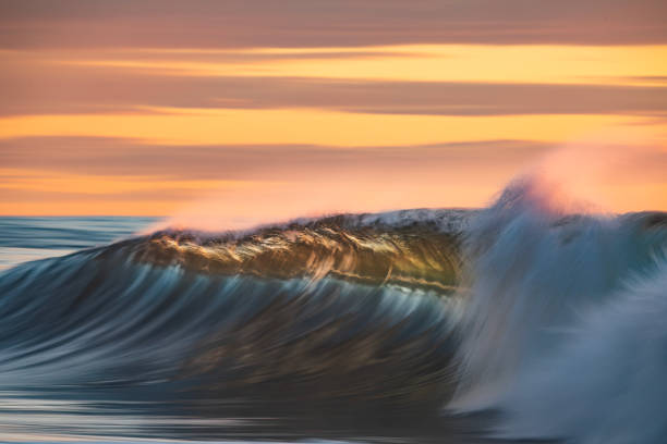 istock Smooth ocean wave breaking in early morning golden light and dramatic sky at sunrise 1463337131