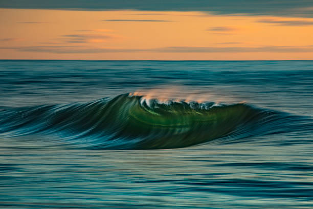 istock Smooth ocean wave breaking in early morning golden light and dramatic sky at sunrise 1463337177