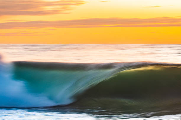istock Smooth ocean wave breaking in early morning golden light and dramatic sky at sunrise 1463337741