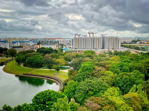 Wide view of water catchment in Bedok Reservoir Park and public housing under construction on cloudy day - Singapore