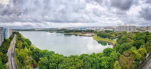 Wide view of water catchment in Bedok Reservoir Park and public housing under construction on cloudy day - Singapore