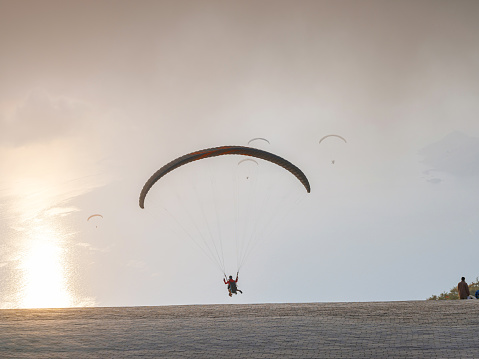 Paragliding in sky. Paraglider tandem flying over sea and mountains in cloudy day. view of paraglider and Blue Lagoon in Oludeniz, Turkey. Extreme sport. Landscape