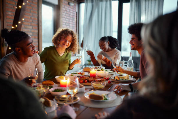 istock Young happy friends talking during dinner at dining table. 1463345445