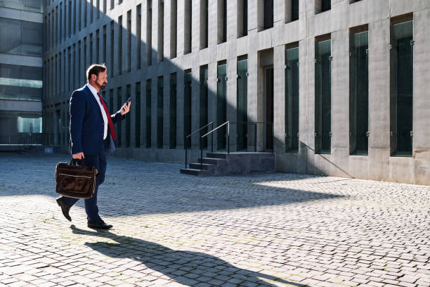 istock Businessman using the mobile while walking in the street 1463345772