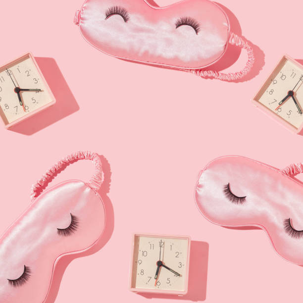 Romantic pattern with pink sleep mask and pink alarm clock on pastel pink background. 80s or 90s retro fashion aesthetic love concept. Minimal cosmetic idea.