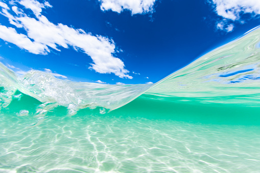 Split image of crystal clear blue water at the beach and a sunny blue sky day.