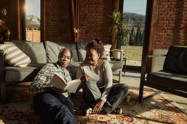 istock Black senior couple reading a book at home. 1463348327