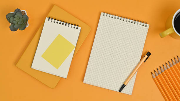 istock Top view of blank notepads, sticky note, pencils and coffee cup on yellow background. 1463350290