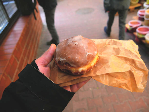istock Traditional polish donut called paczek, in a man hand. 1463360074