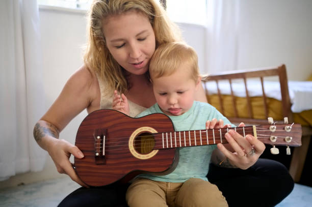 istock Guitar, kid learn and mother with teaching knowledge development at home. Mom, child and toddler together with parent love and care in a house with education toys and instrument for learning 1463362355
