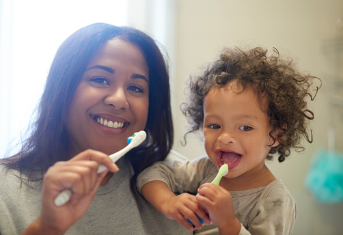 Brushing teeth, mother and baby portrait in bathroom for dental care, learning and cleaning in their home. Face, Oral hygiene and child development by mom teach child mouth, teeth and grooming care