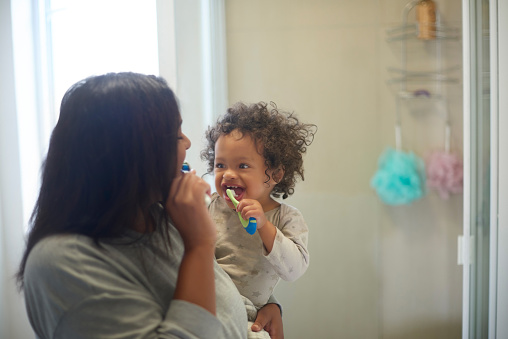 Dental health, baby and mother brushing teeth in bathroom, learning and cleaning in their home. Oral hygiene, child development and mom teaching child about mouth, teeth and smile, happy and together