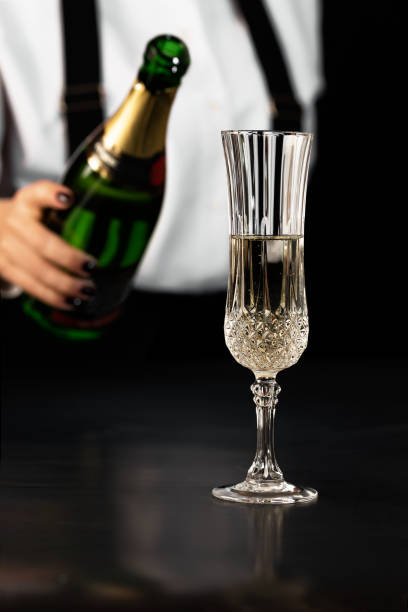 istock the bartender pours champagne from a bottle in a crystal glass on a dark background 1463364021