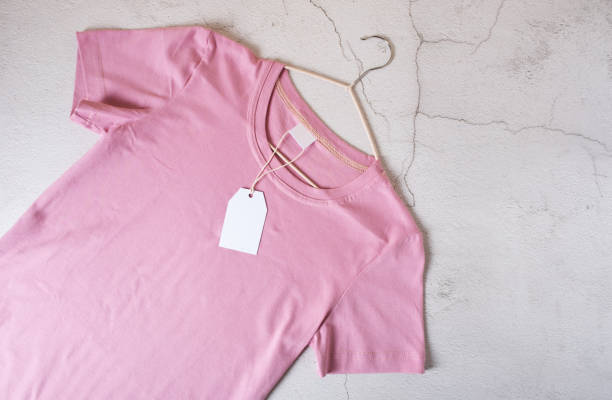 istock Pink T-shirt on a hanger with a tag on a light concrete background 1463364848