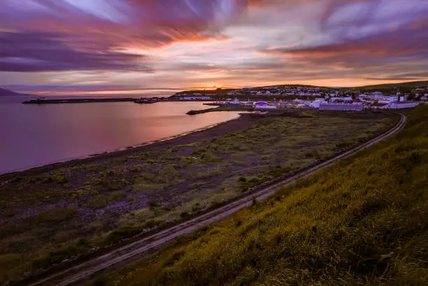 The beautiful sunset above the sea and the town. Husavik, Iceland.