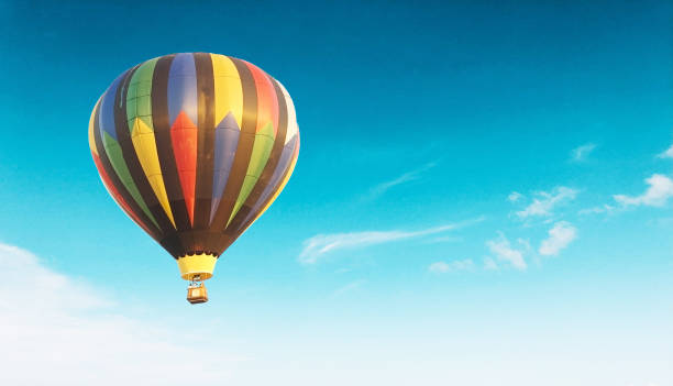 istock Colorful air baloon flying high in the blue sky with clouds floating around it 1463372568