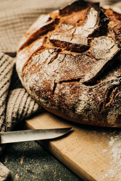 istock Freshly-baked bread loaf on a wooden board 1463372954