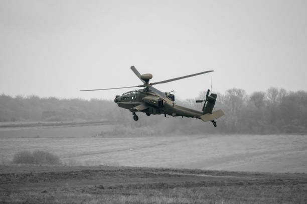 Dark grey army attack helicopter in very low level flight