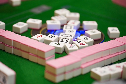 An Asian man is enjoying mahjong game at home.