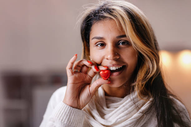 le mani delle donne con una manicure luminosa tengono una caramella al cioccolato a forma di cuore - heart shape cute valentines day nostalgia foto e immagini stock