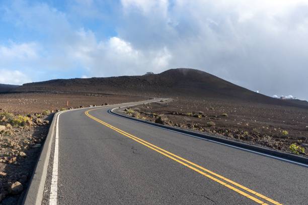 istock Empty curving road in the wilderness surrounded by dry fields and low hills under a cloudy sky 1463374583