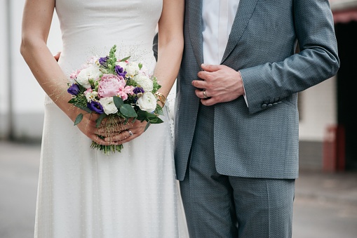 A closeup of the bride holding her beautiful bouquet while standing next to the groom