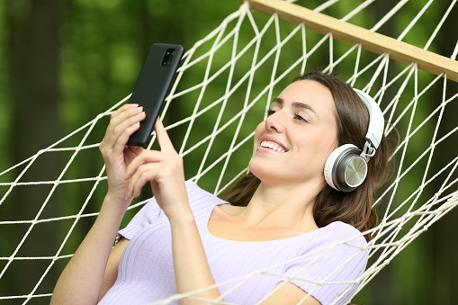 Happy woman on hammock listening music