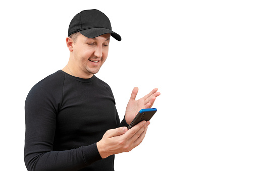 Young man in a baseball cap using a smartphone on a white background. Lifestyle