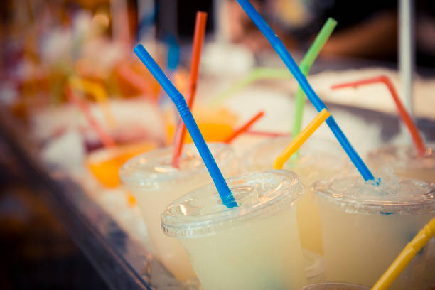Close-up overhead shot of a nearly empty glass of light teal beverage with a straw, on a teal table in Bengaluru, India.