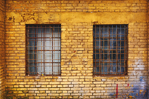 Old grid windows with dirty glass on exterior wall of an old abandoned factory warehouse building