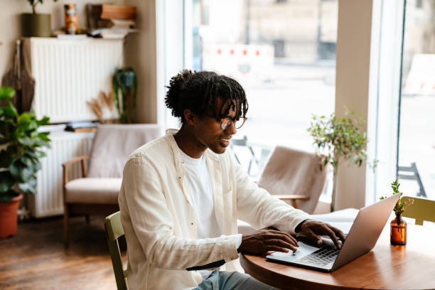 istock Young african man working on laptop while sitting in cafe 1463381946