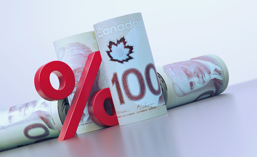 Rolled up 100 Canadian Dollar bills and red percentage sign over grey background. Horizontal composition with copy space. Finance concept.