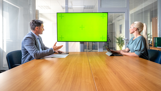 Businessman with colleague looking projection screen during meeting in office.