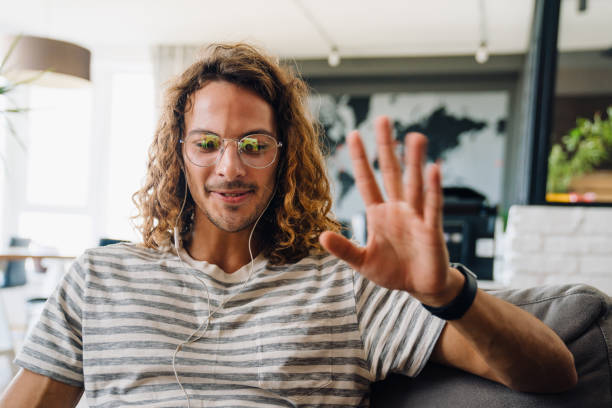 istock Young man smiling and gesturing at laptop sitting at sofa in office 1463384308