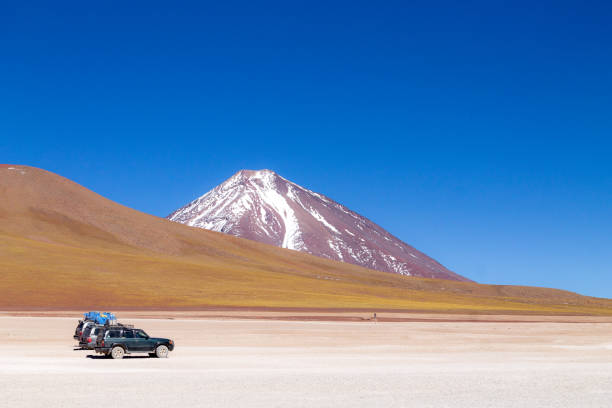 beautiful shot of off road vehicles under licancabur volcano in bolivia - white lake imagens e fotografias de stock
