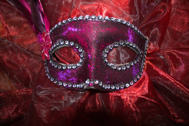 A purple carnival mask on bright red cloth
