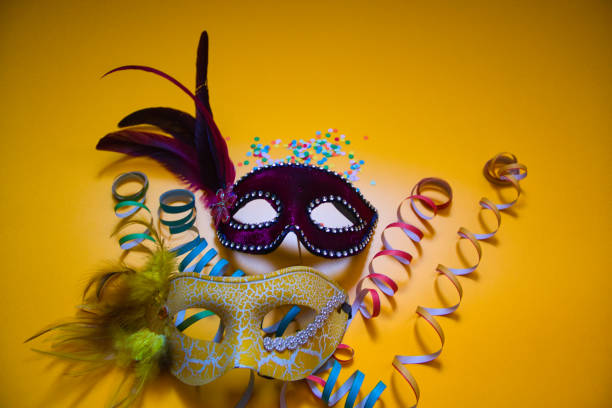istock Two carnival masks with confetti and curly paper on a yellow background 1463385128