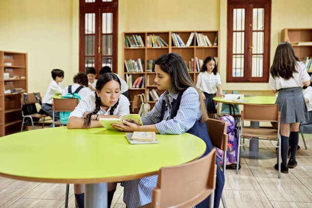 Schoolgirl and instructor reading together in library