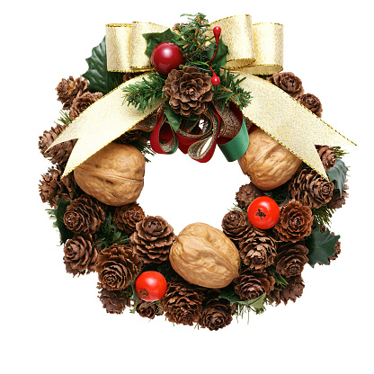 Round Christmas wreath made of dried cones and walnuts on a white background.