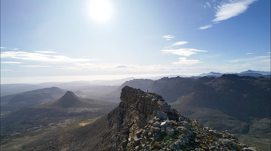 Far away image of a hiker trail runner standing on top of a mountain summit ridge in the Southern Cederberg.  The person is standing on The Pup at Kromrivier.