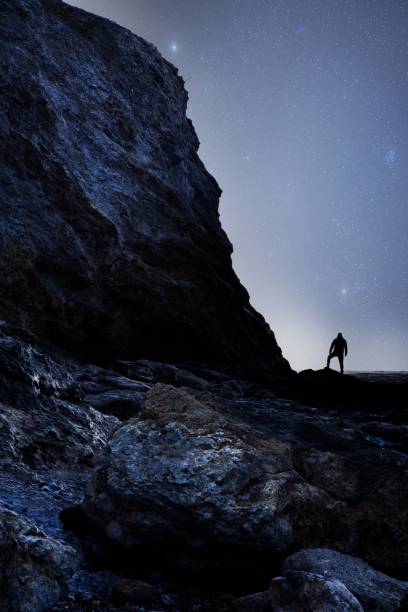 istock Silhouette of a man standing on the rock under a night sky 1463387191