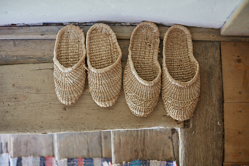 A top view of wicker flip-flops on the floor at the entrance of an old house
