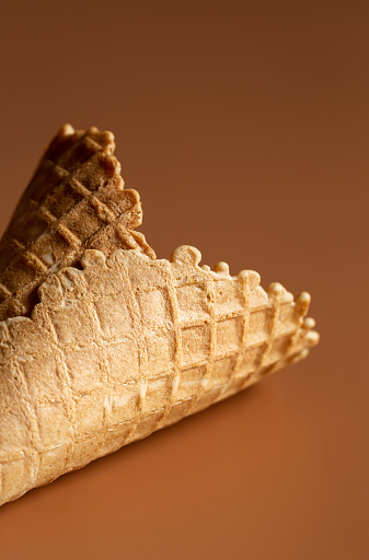 Textured waffle cone on a brown background isolated, for dessert and ice cream. Creative macro concept of sweets and food.