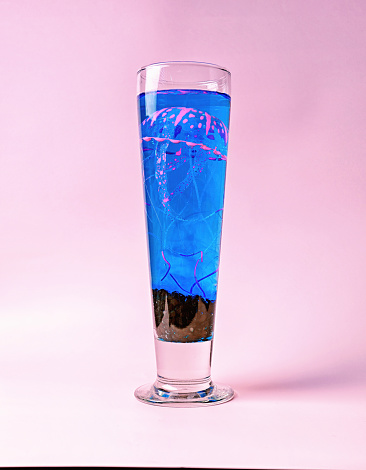 Electric Jellyfish: A Neon Pink and Blue Medusae in a Beer Glass on a Pink Background - Marine Life and Aquarium Event Concept