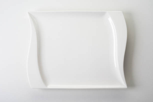 istock Top view of a square white ceramic plate with wavy edges on white background 1463391152