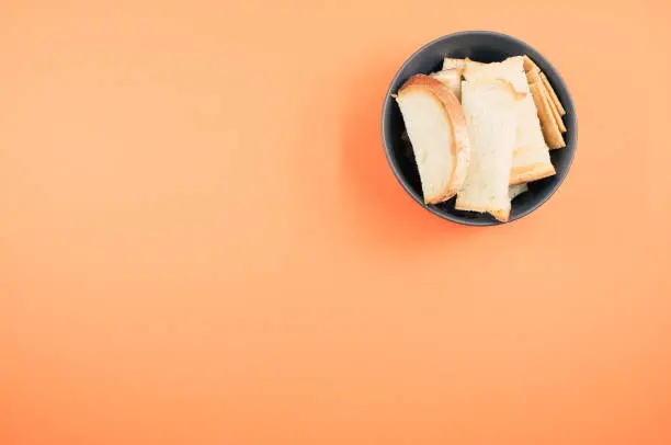 A top view of bread slices on a bowl isolated on an orangebackground
