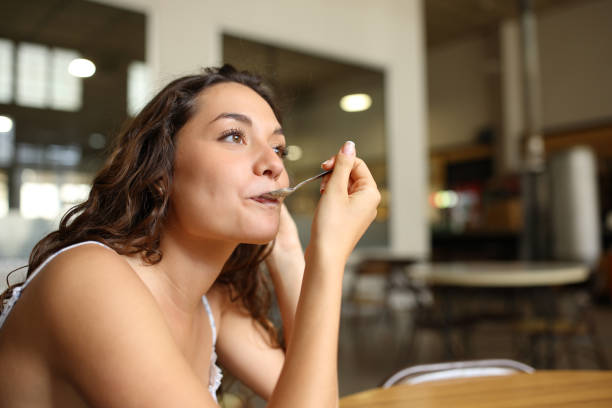 mujer usando cuchara en una cafetería - mujer boca fotografías e imágenes de stock