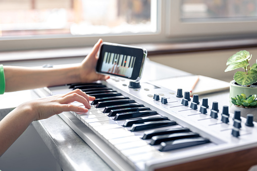 A child learns to play the piano with a smartphone, online music lesson, self-study with the help of video.