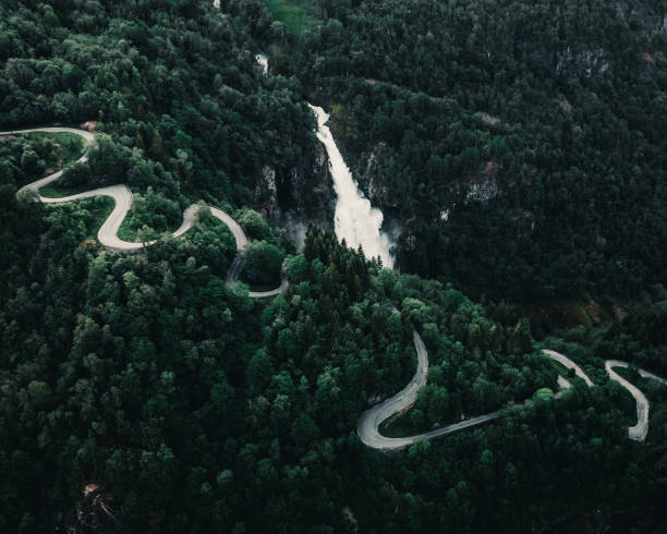istock Aerial view of a winding road passing through forests with a rapidly flowing waterfall next to road 1463399467
