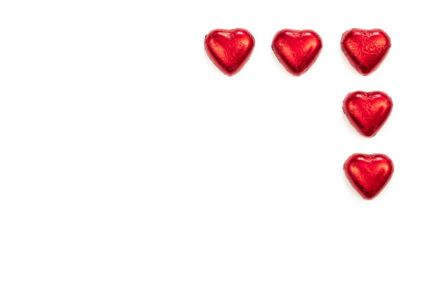 Red heart shaped chocolate candies on white background isolated, flat lay, copy space.